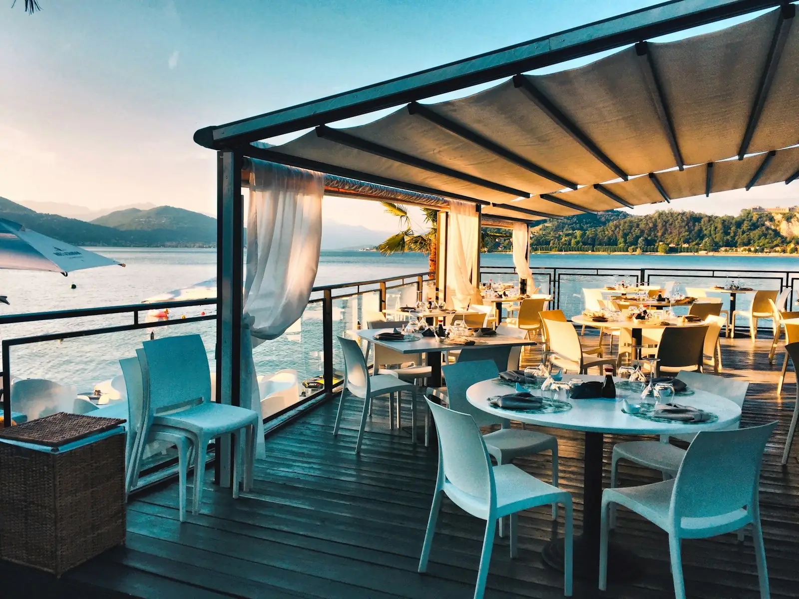 A waterside restaurant terrace set for dinner at golden hour